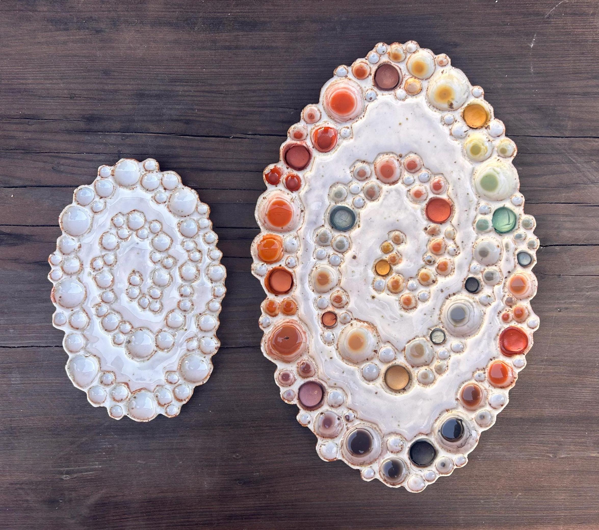 Mini and large size ceramic oval spiral bubble palettes beside each other on a wooden surface 