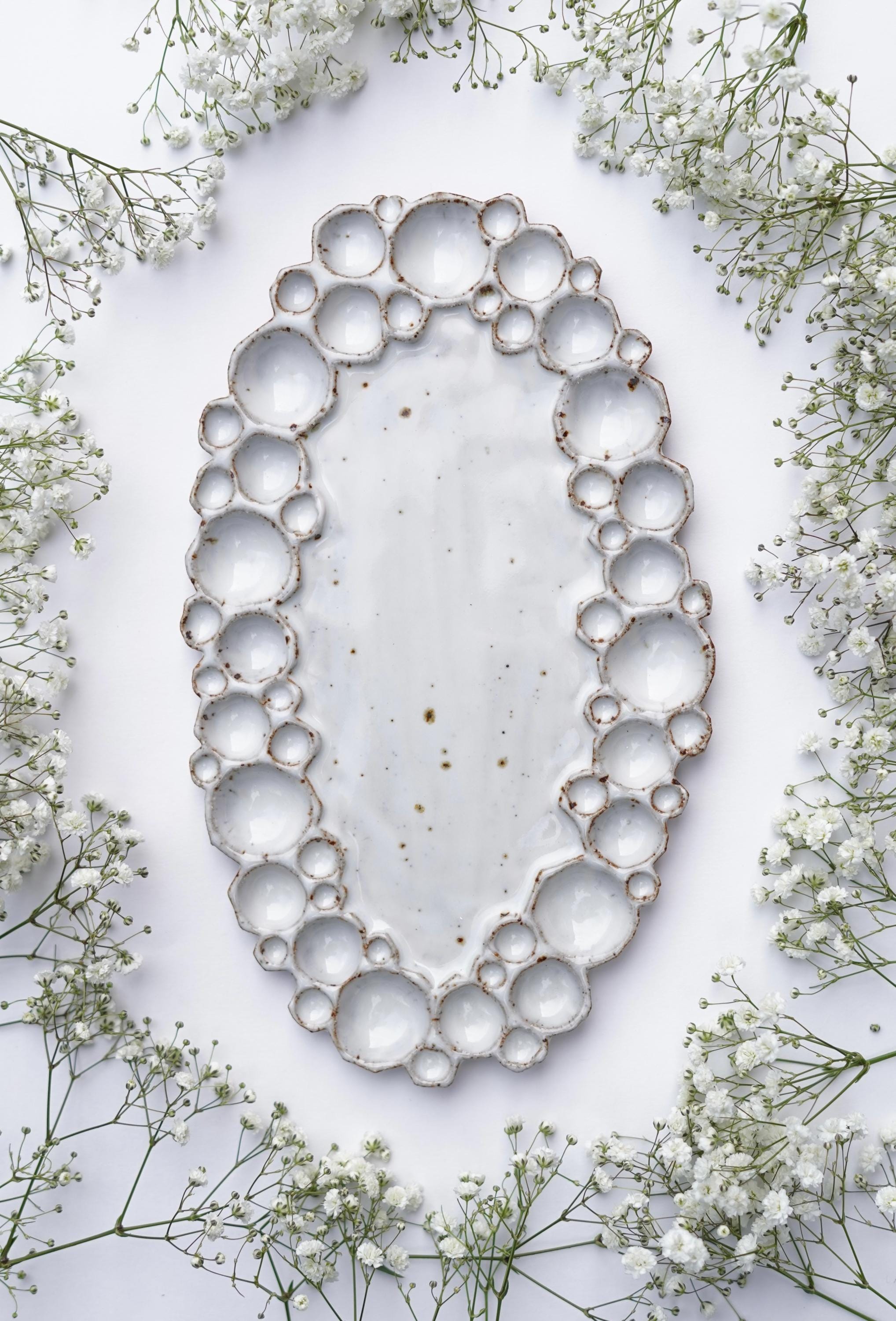 Large ceramic oval bubble palette against white background with flowers 