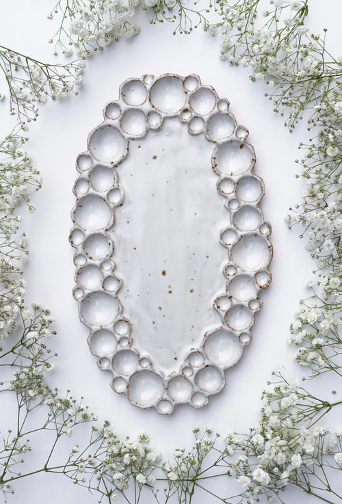 Large ceramic oval bubble palette against white background with flowers 