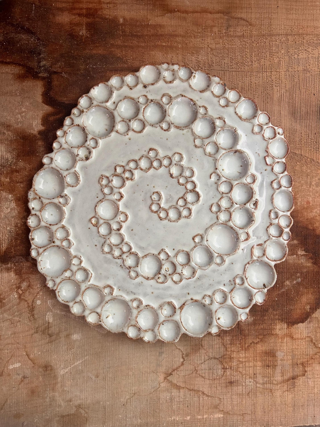 Large round ceramic spiral bubble palette on wooden surface 