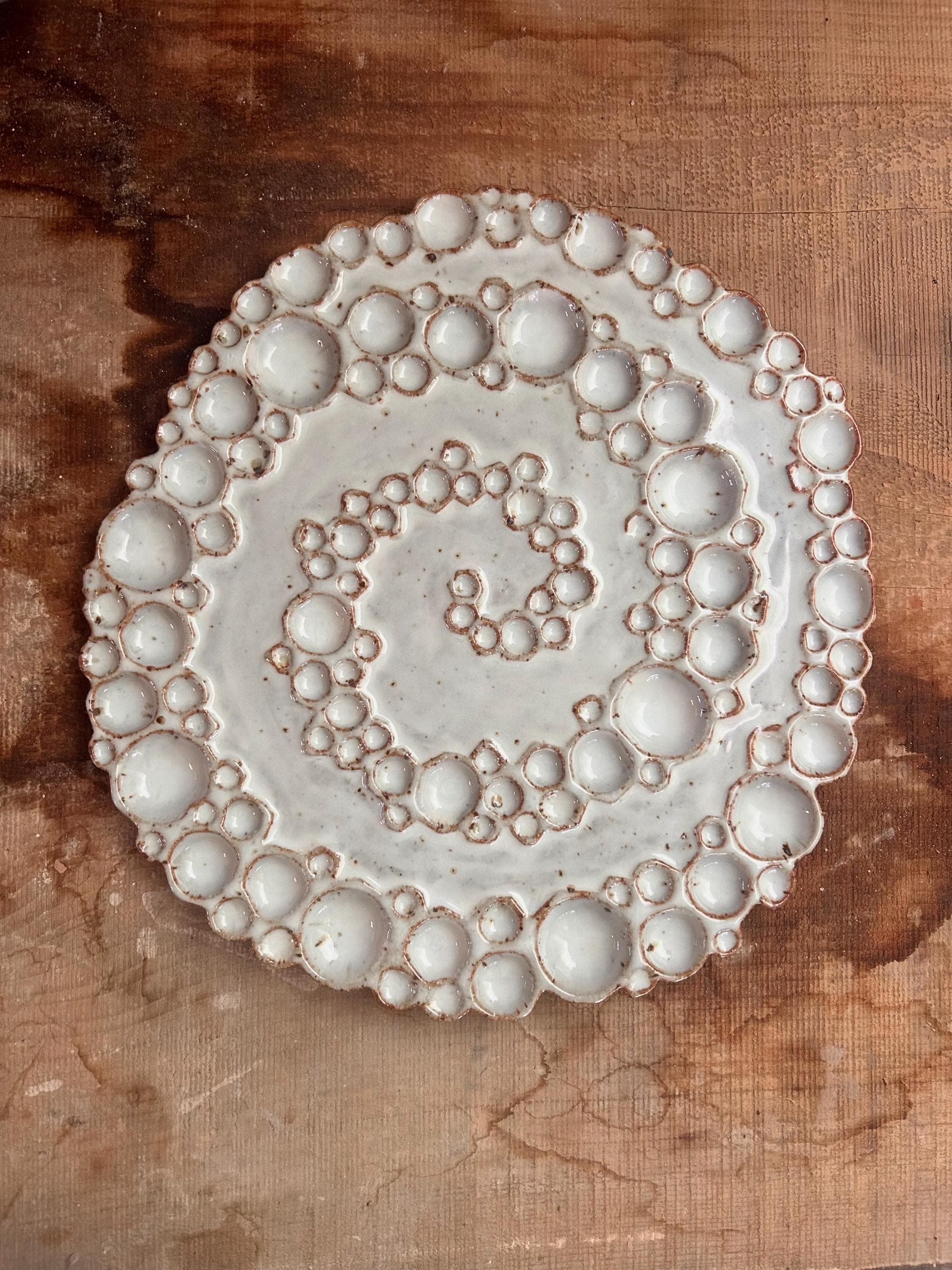 Large round ceramic spiral bubble palette on wooden surface 