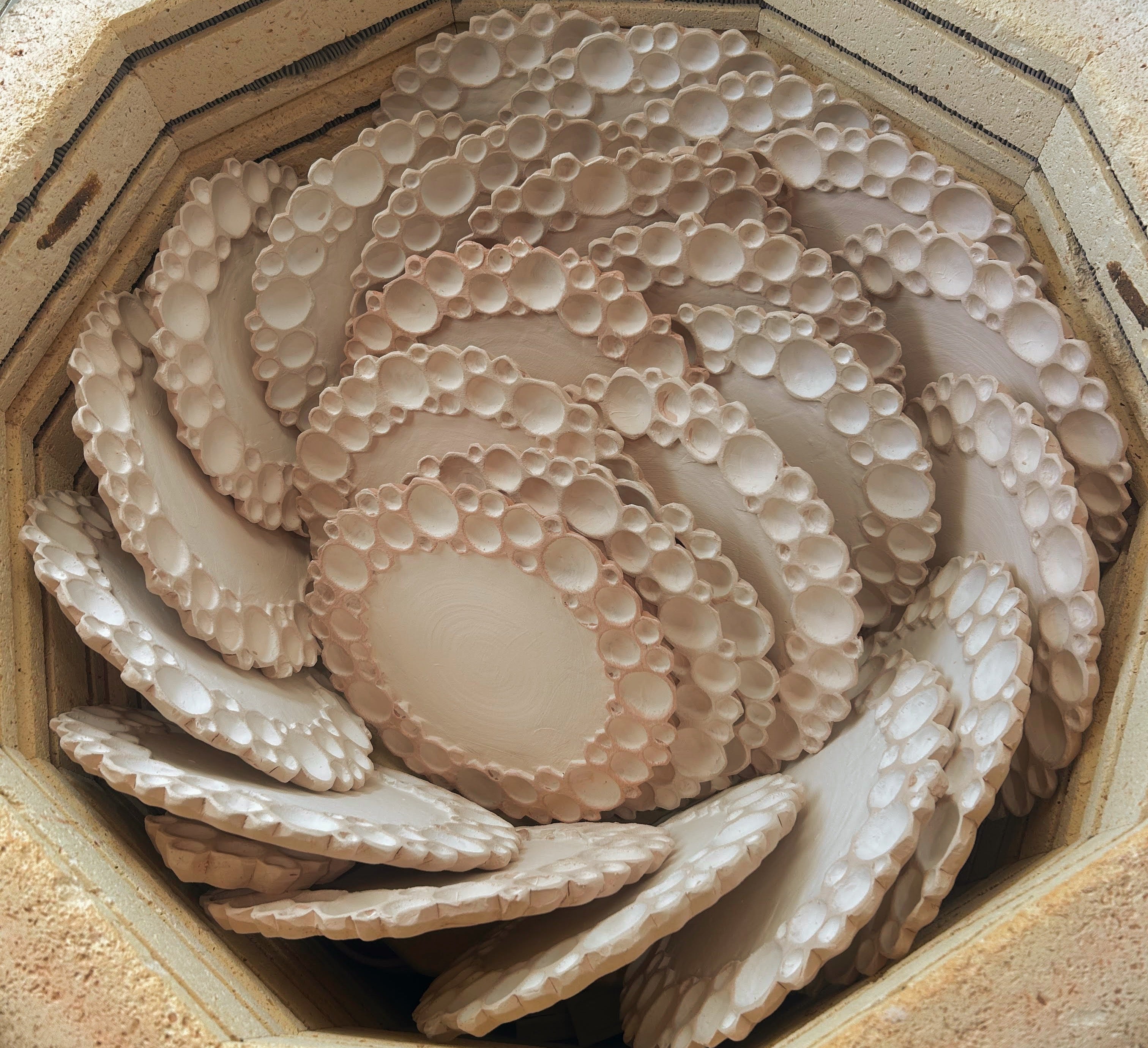 Round bubble paint palettes stacked on their sides in a kiln