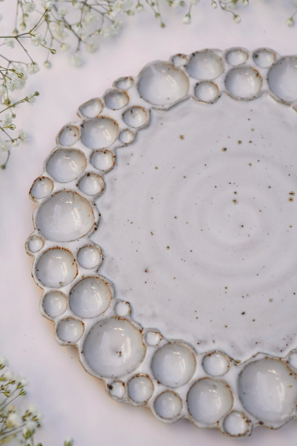 Round bubble paint palette from a side angle with white background and flowers around it 