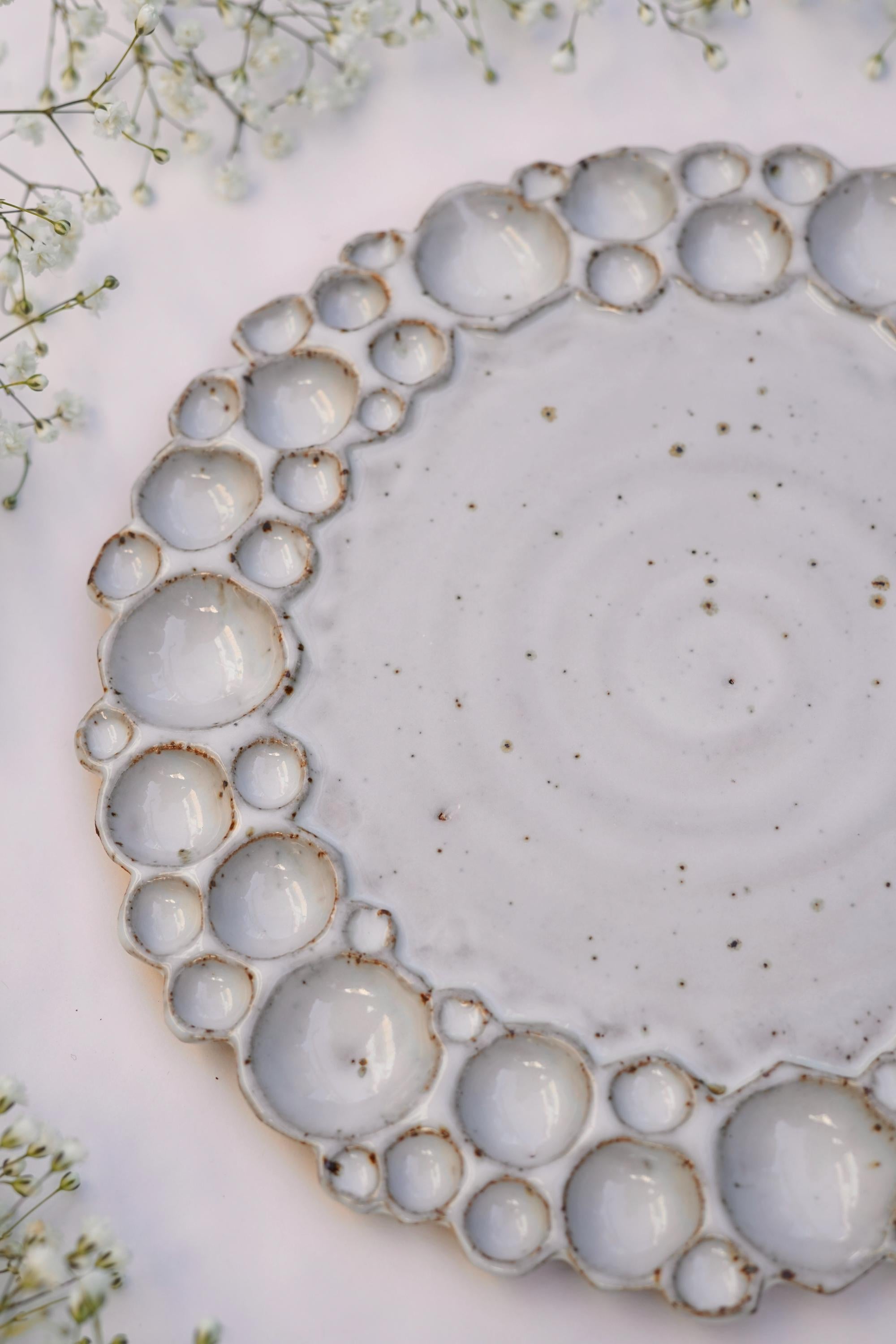 Round bubble paint palette from a side angle with white background and flowers around it 