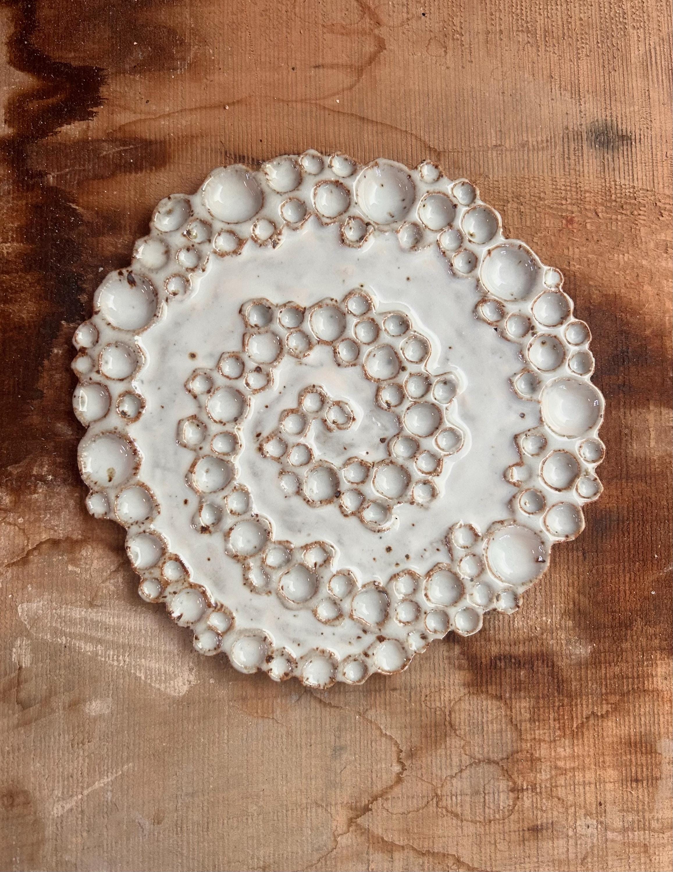 Small round ceramic spiral bubble palette on wooden surface 