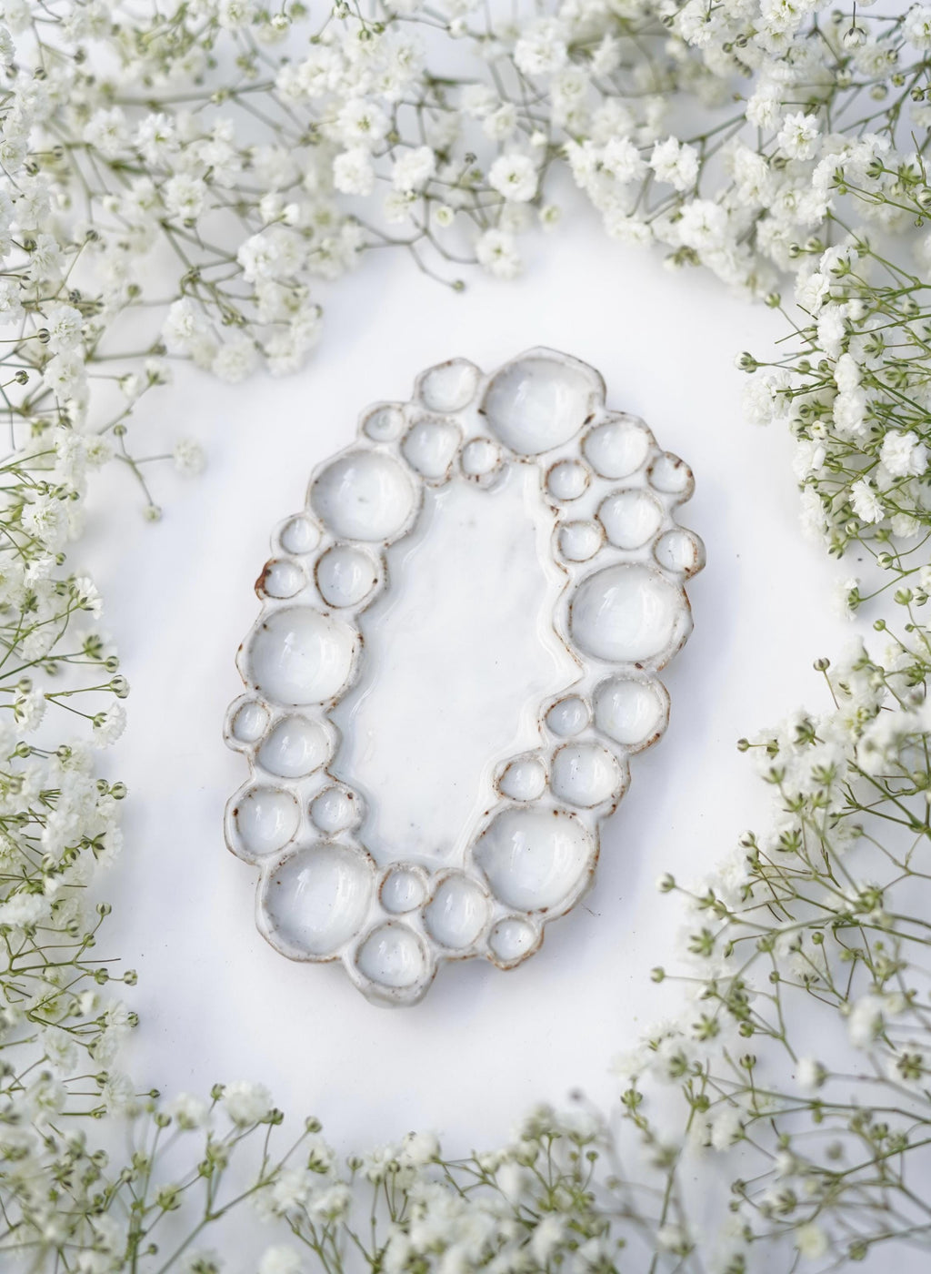 Side view of mini ceramic oval bubble palette against white background with flowers