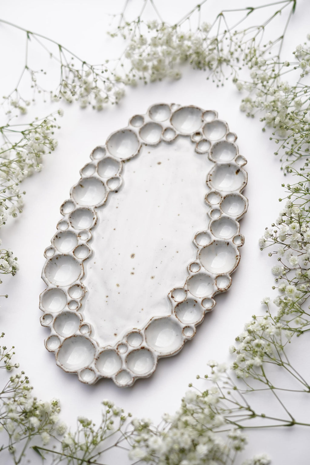 Side view of large ceramic oval bubble palette against white background with flowers 