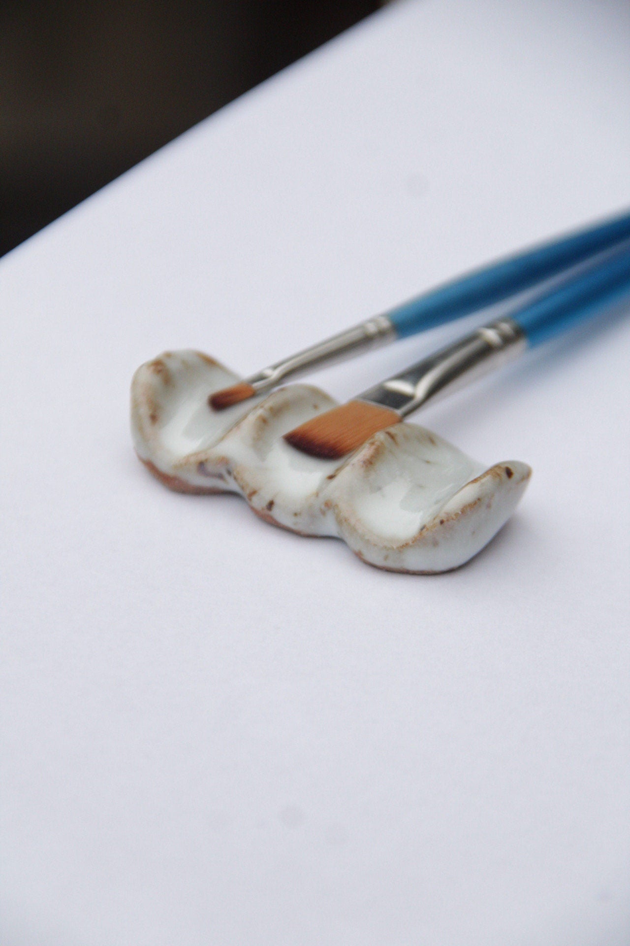 Ceramic brush rest with paint brushes against white background 