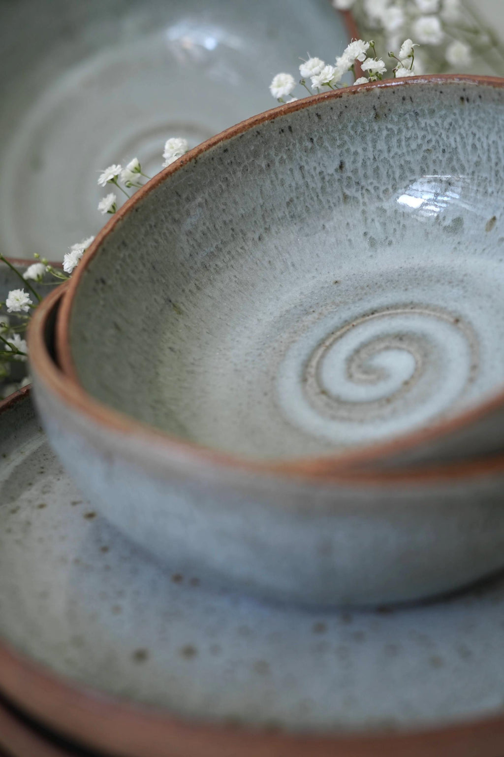 Close-up of a light blue ceramic bowl with a spiral design on a matching plate.