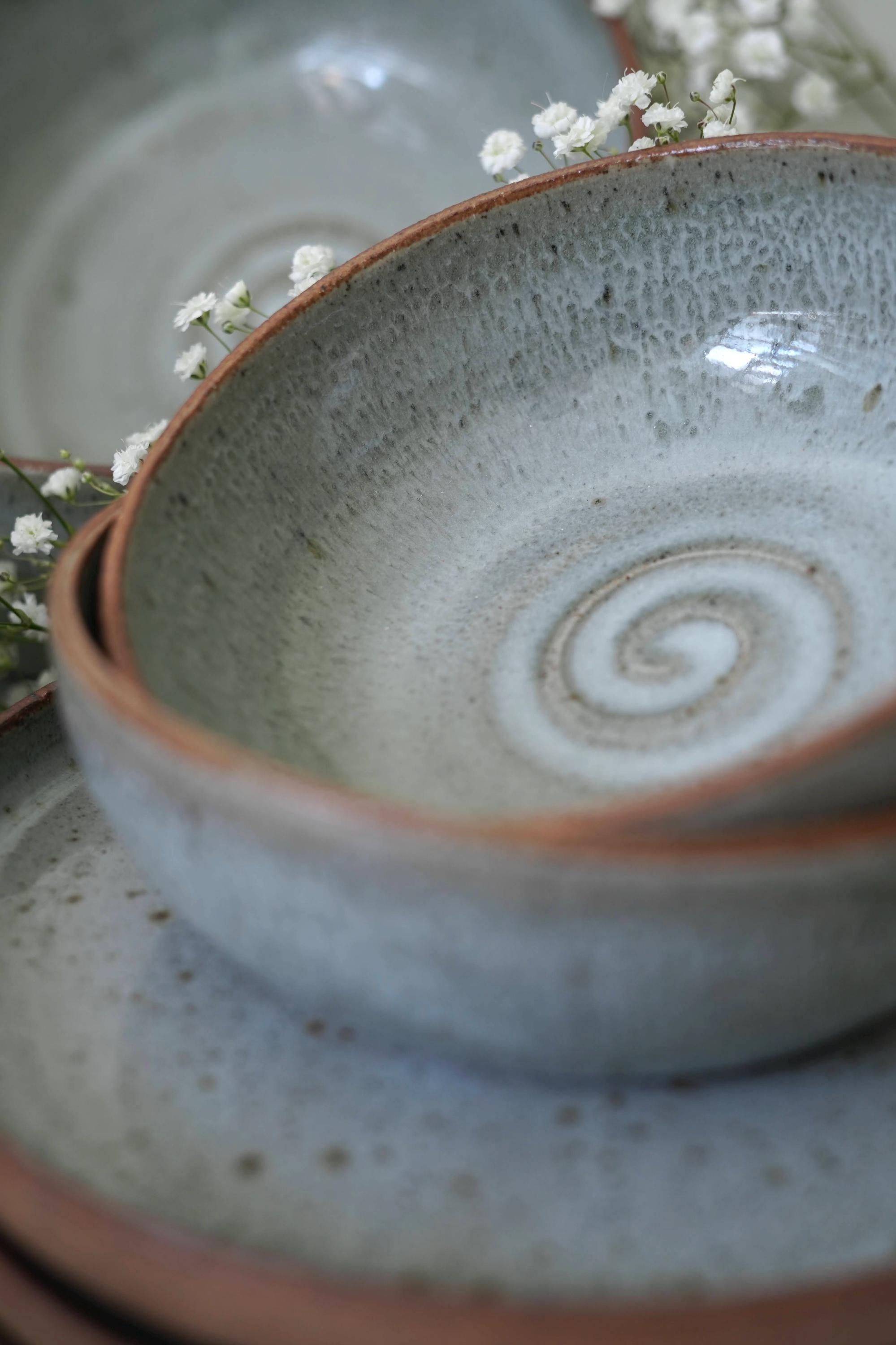 Close-up of a light blue ceramic bowl with a spiral design on a matching plate.